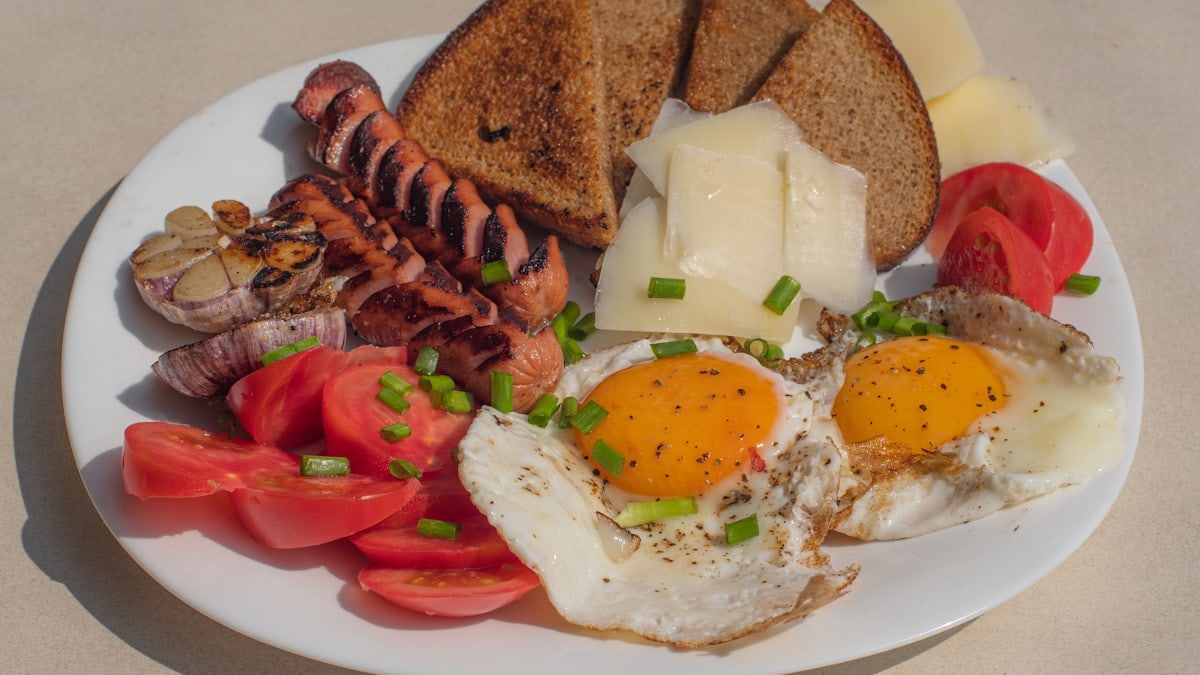 a white plate topped with eggs, toast, tomatoes and meat